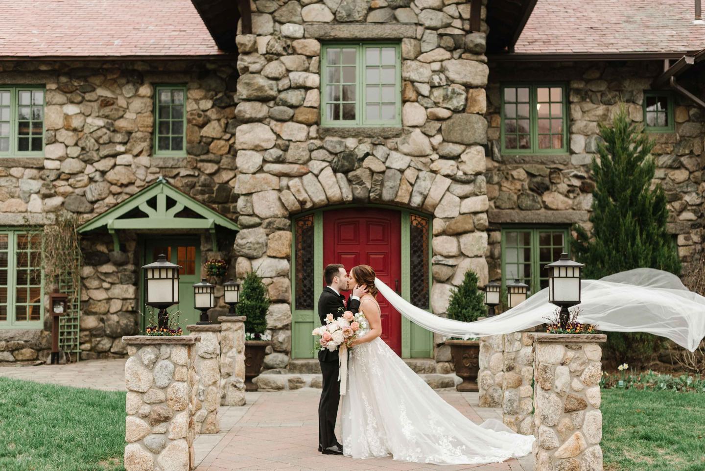 Couple outside wedding venue with veil in wind