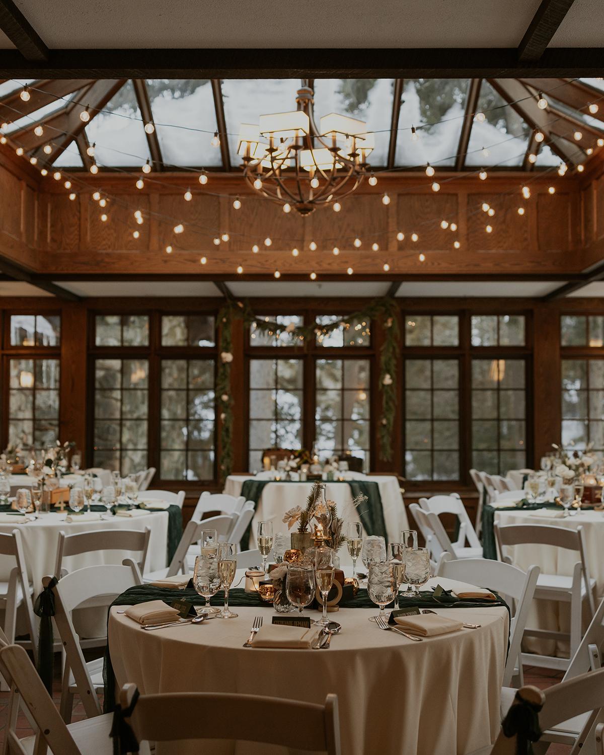 Cozy banquet hall with elegant tables, chandeliers, and large windows.