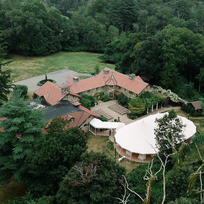 Mansion with red roofs and garden, surrounded by trees, aerial view.
